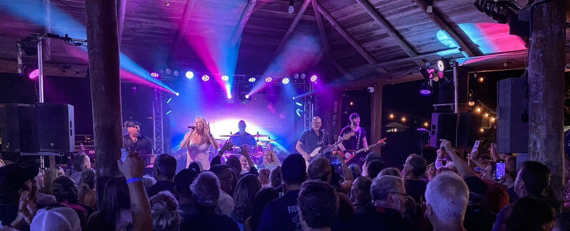 band playing live music to a crowd under a tiki roof