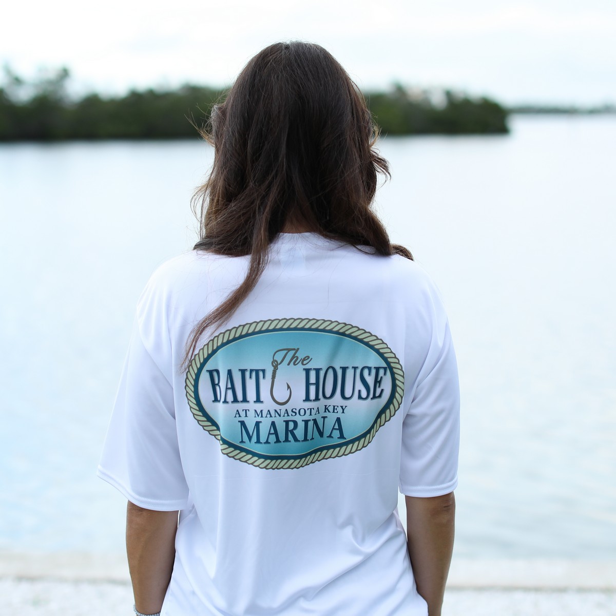 woman wearing The Bait House at Manasota Key Marina Unisex Performance T-Shirt in white - back