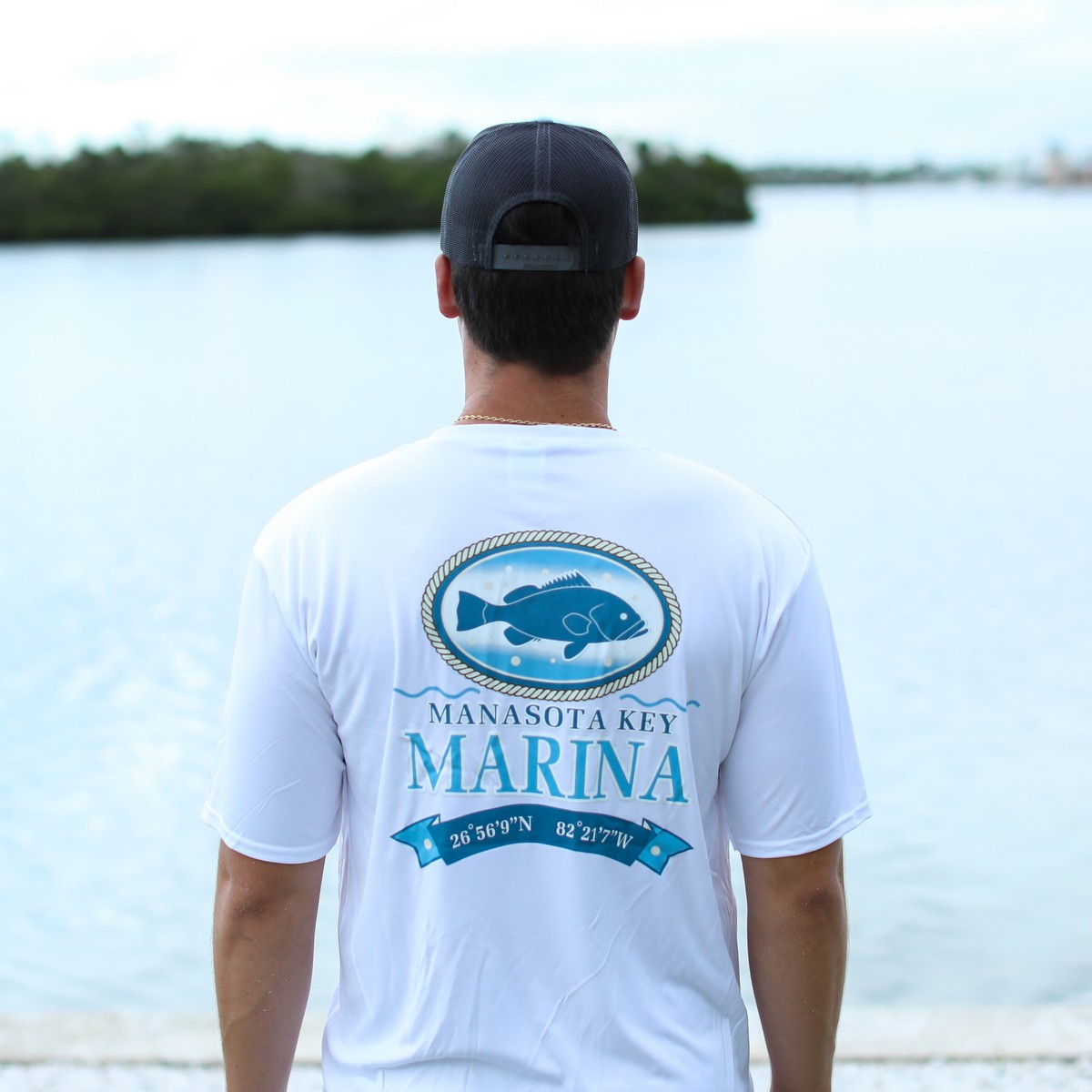 man wearing Manasota Key Marina Unisex Performance T-Shirt in white - back