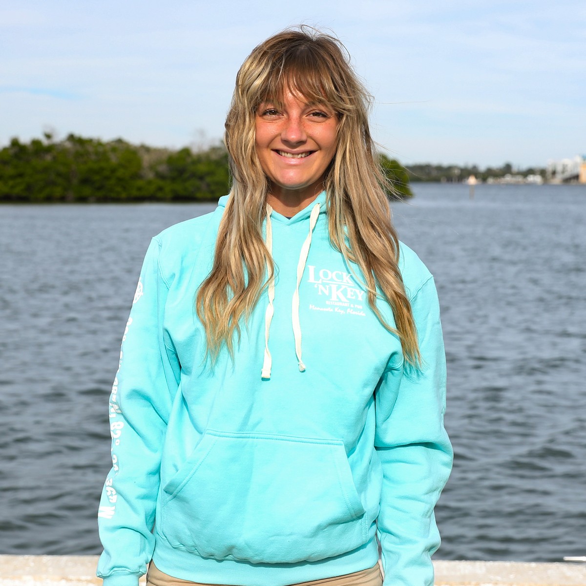 woman wearing Lock 'N Key Unisex Fleece Hooded Sweatshirt with intracoastal waterway in the background