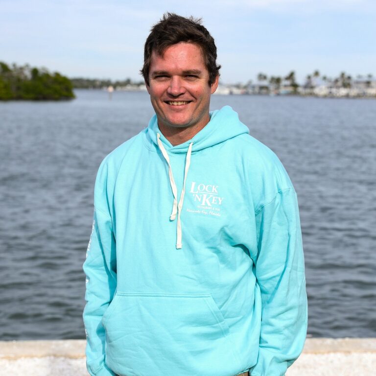 man wearing Lock 'N Key Unisex Fleece Hooded Sweatshirt with intracoastal waterway in the background