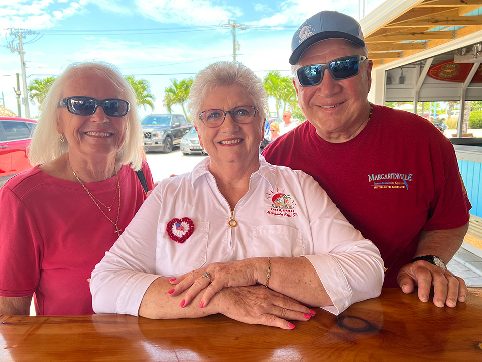 Linda Lyon posing with two SandBar Tiki & Grill customers